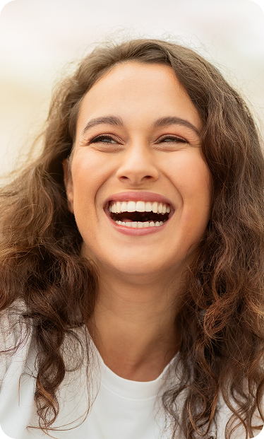 A smiling woman with clear, bright eyes and rejuvenated skin, illustrating the benefits of IPL dry eye treatment.